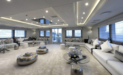 Chakra yacht interior: expansive white lounge with gray cushions, metallic ottomans, and glass coffee tables