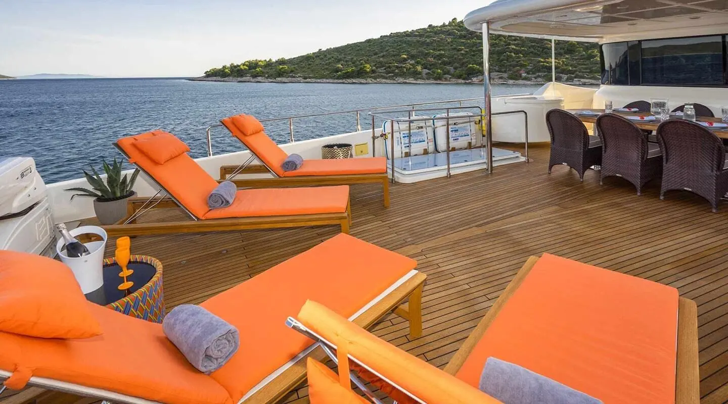 Sun loungers with orange cushions on a yacht deck at sunset