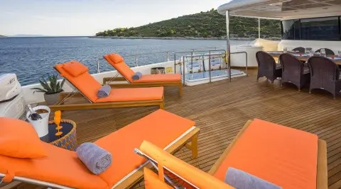 Sun loungers with orange cushions on a yacht deck at sunset