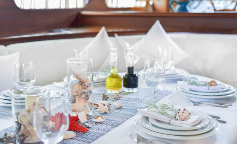 Elegant yacht dining table on deck with glassware, plates, cutlery, and seashell decorations