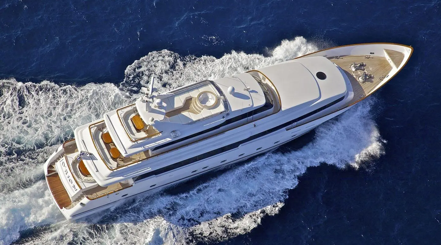 Overhead view of a sleek white luxury yacht cruising blue sea near wake