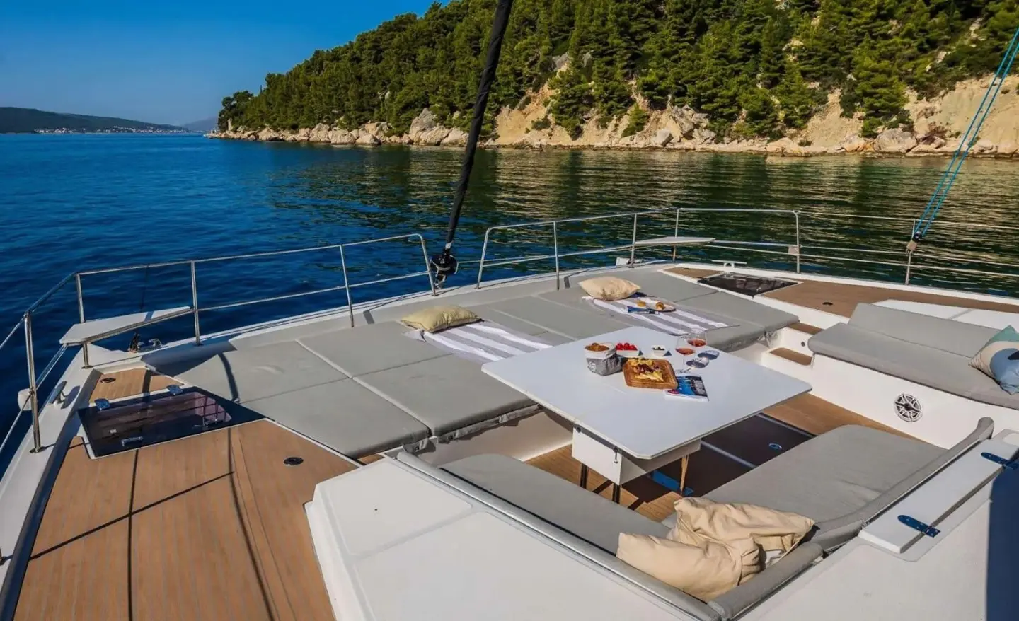 Sunlit yacht deck with a table, seating area, and sunset over calm water
