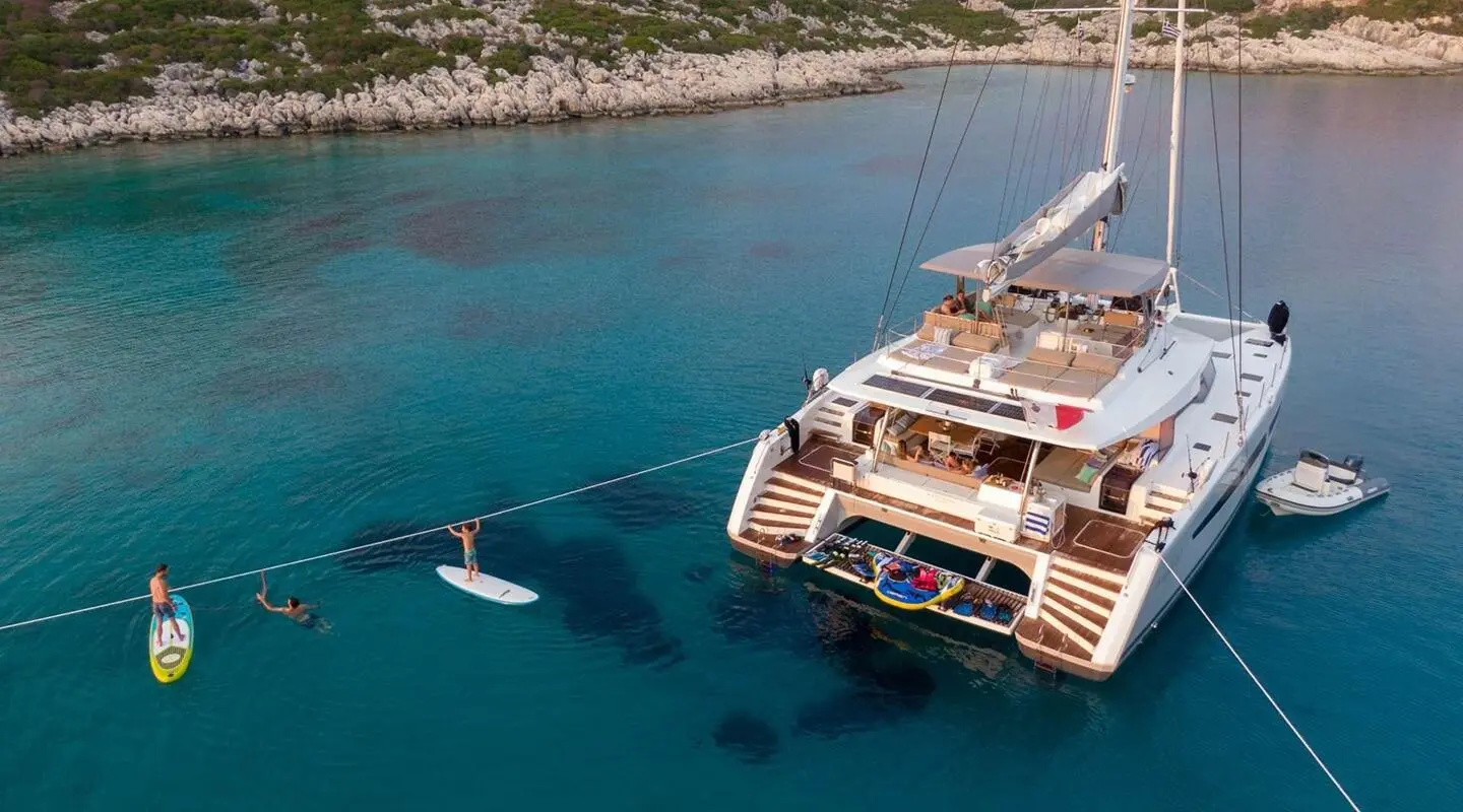 Serenissima yacht in open sea with large deck and docked near rocky shore