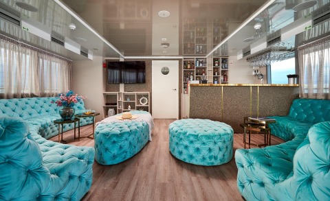 Ohana yacht interior lounge with turquoise tufted seating, tables, bar and TV