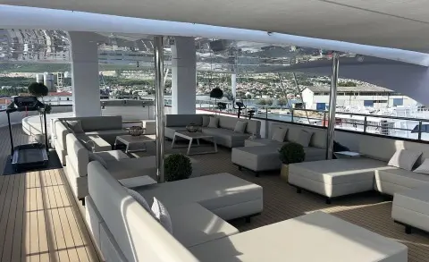 Salon on Melody yacht with cream seating, glass windows, and outdoor marina view
