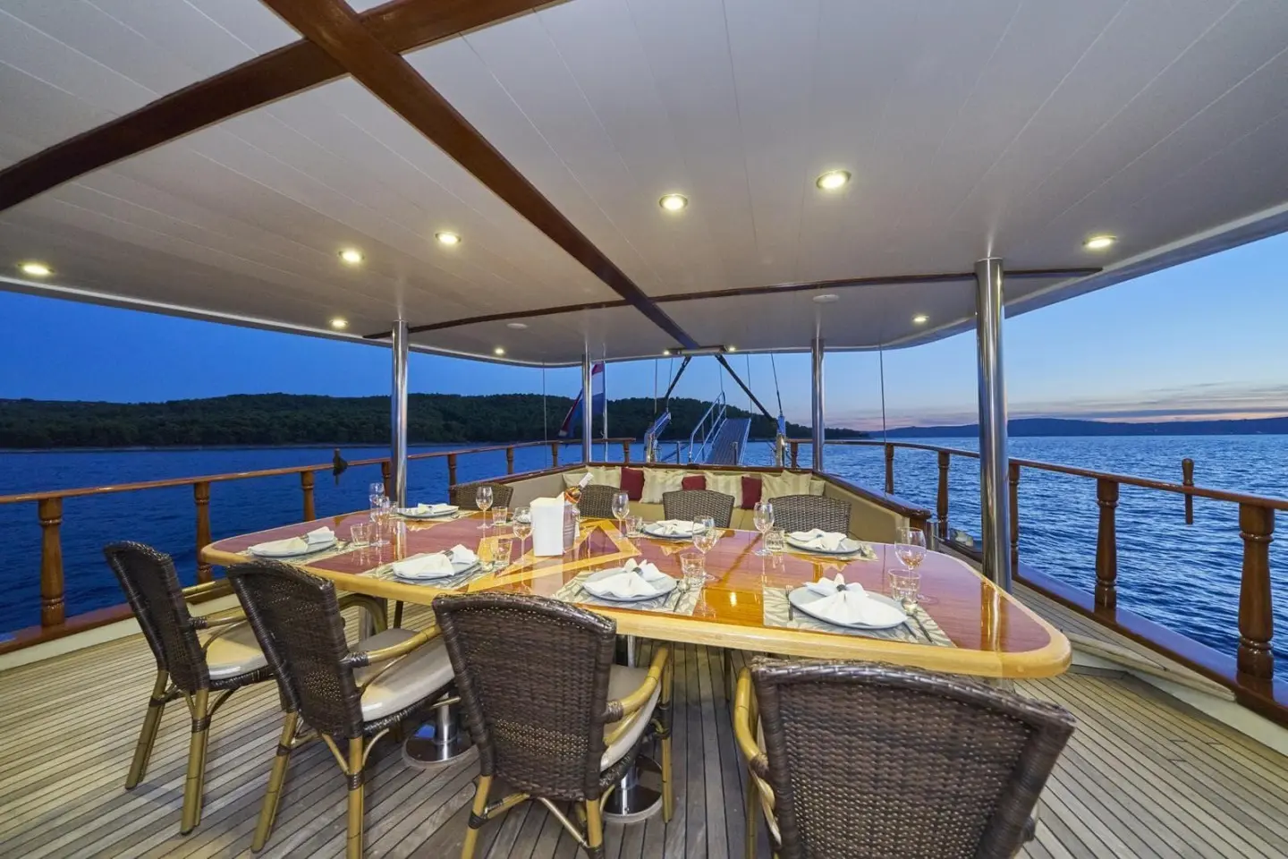 A gulet-style yacht aft deck dining area under a covered canopy with seating