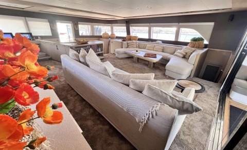 Luxurious yacht interior with a large seating area, sectional sofas, coffee table and decorative cushions