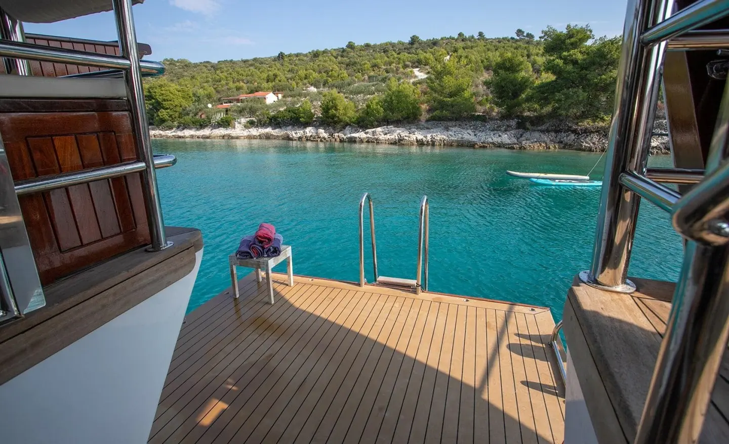 Amorena motor yacht deck with swim platform, turquoise water, and coastline