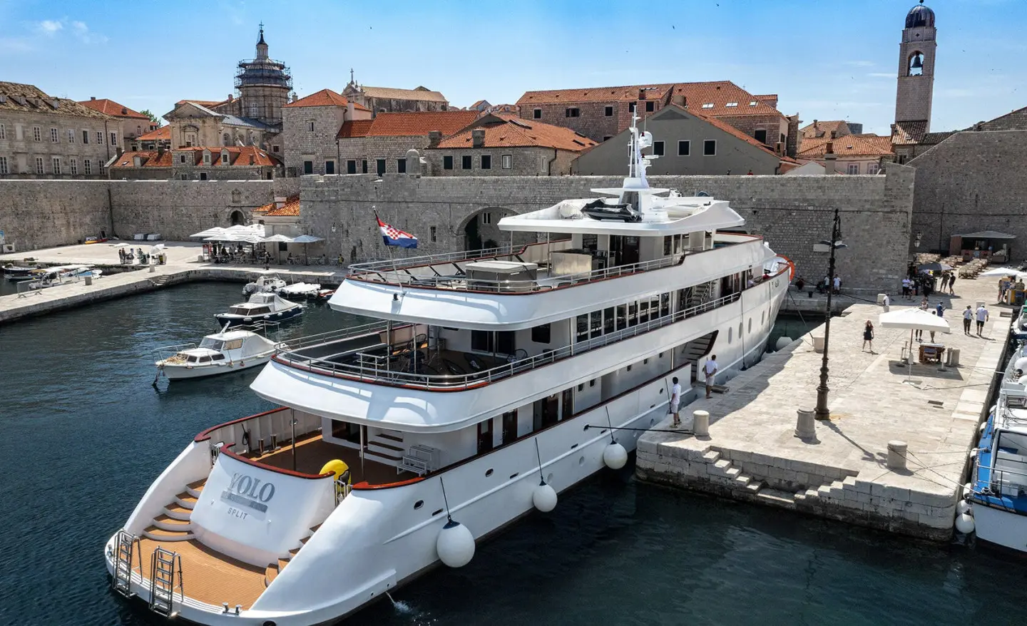 Yolo luxury yacht docked at a sunny Dubrovnik harbor with stone walls