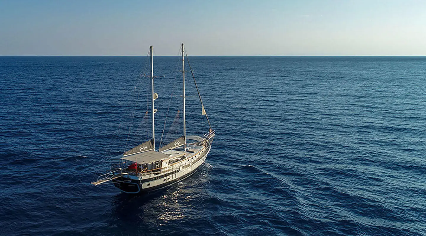 Sailing yacht with two masts in open sea, gulet-like vessel photographed from above