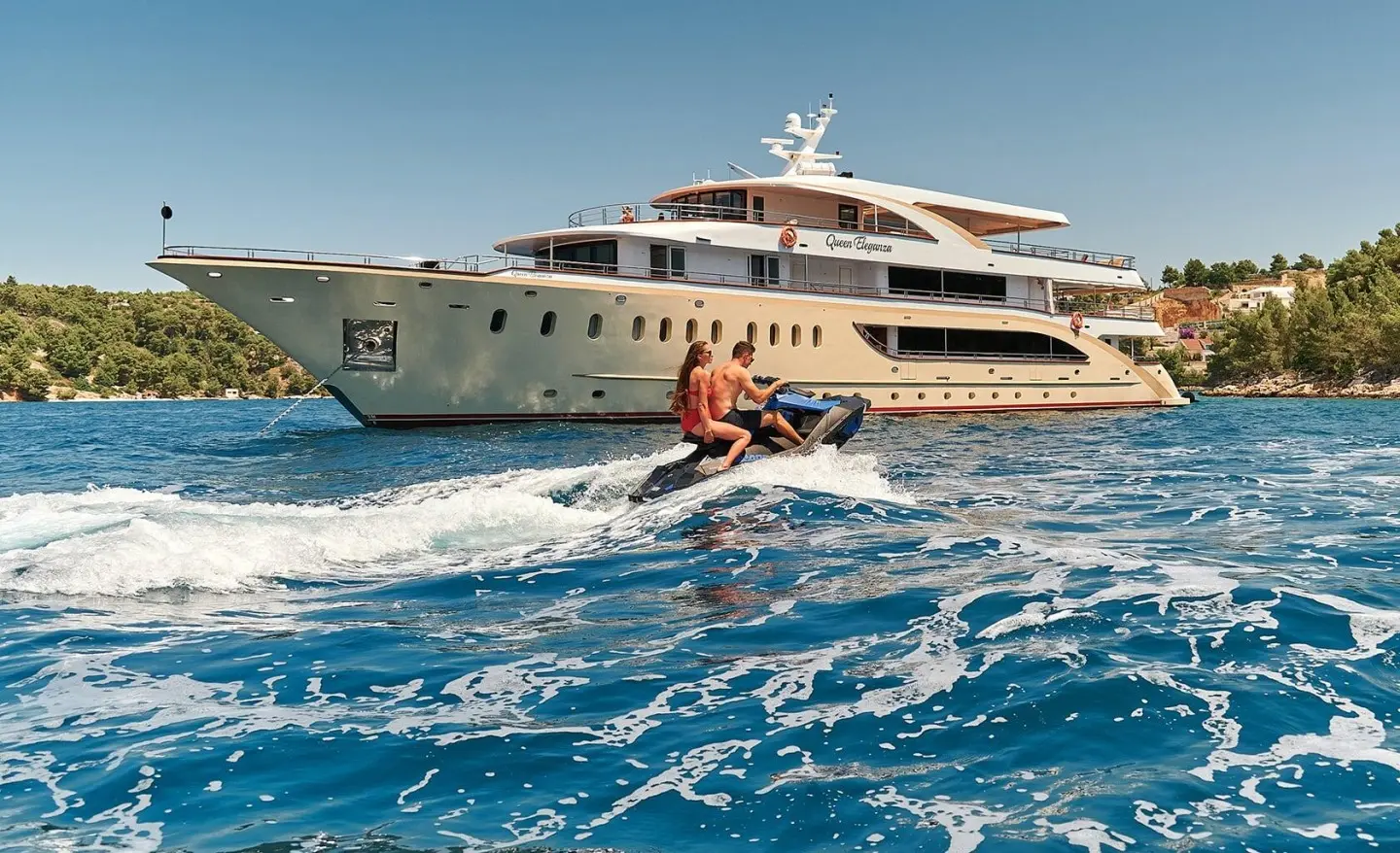 Queen Eleganza yacht anchored near clear blue water with a person swimming nearby