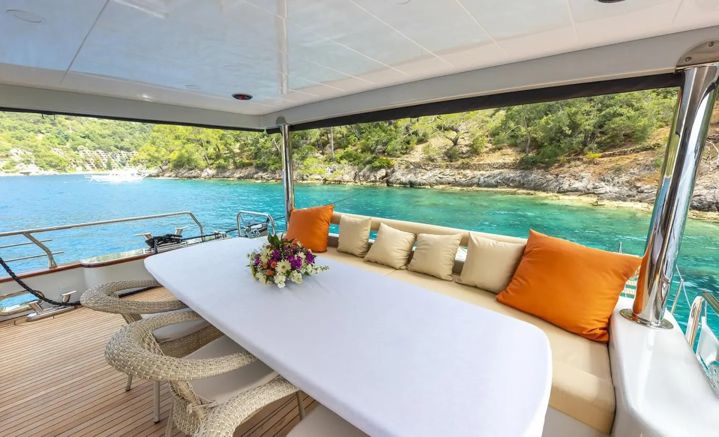 aft deck of Simay M yacht with white table, orange cushions, and pool view