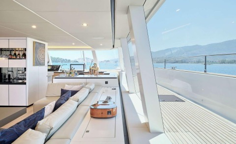 Genny luxury yacht interior: white satin seating, bar area, guitar on deck, panoramic water view