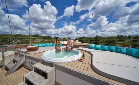On a sunny outdoor deck, a luxury yacht's jacuzzi with turquoise cushions along the edge
