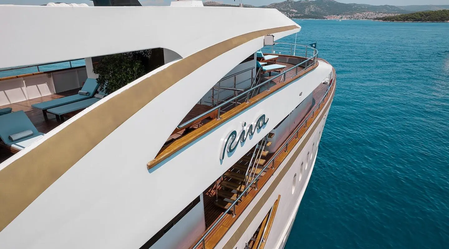 Riva luxury yacht with white hull, teak decks, and sun loungers aboard