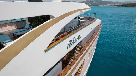 Riva luxury yacht with white hull, teak decks, and sun loungers aboard