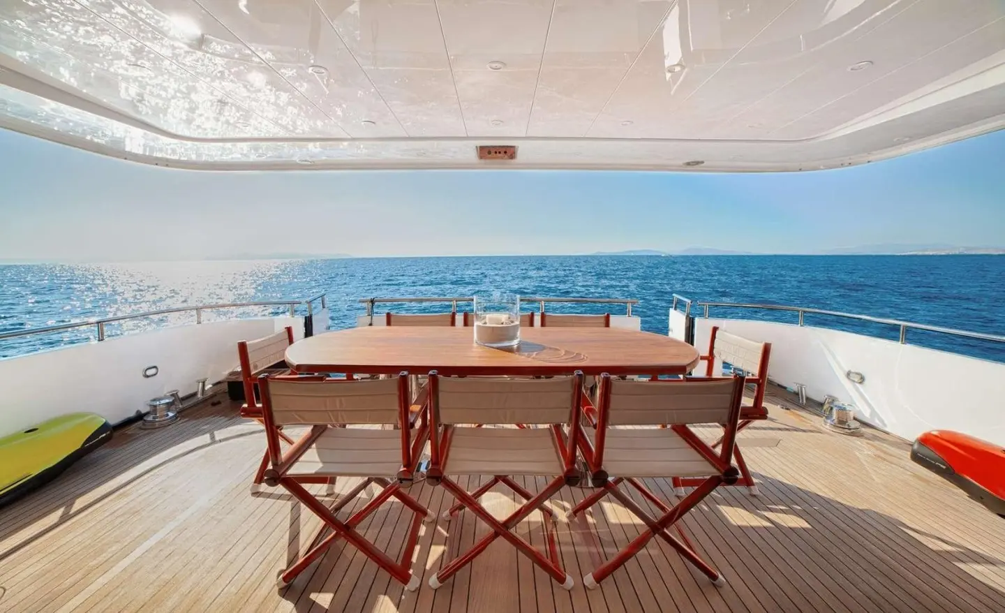 Dining deck on luxury yacht Zoi with wooden table and chairs overlooking sea