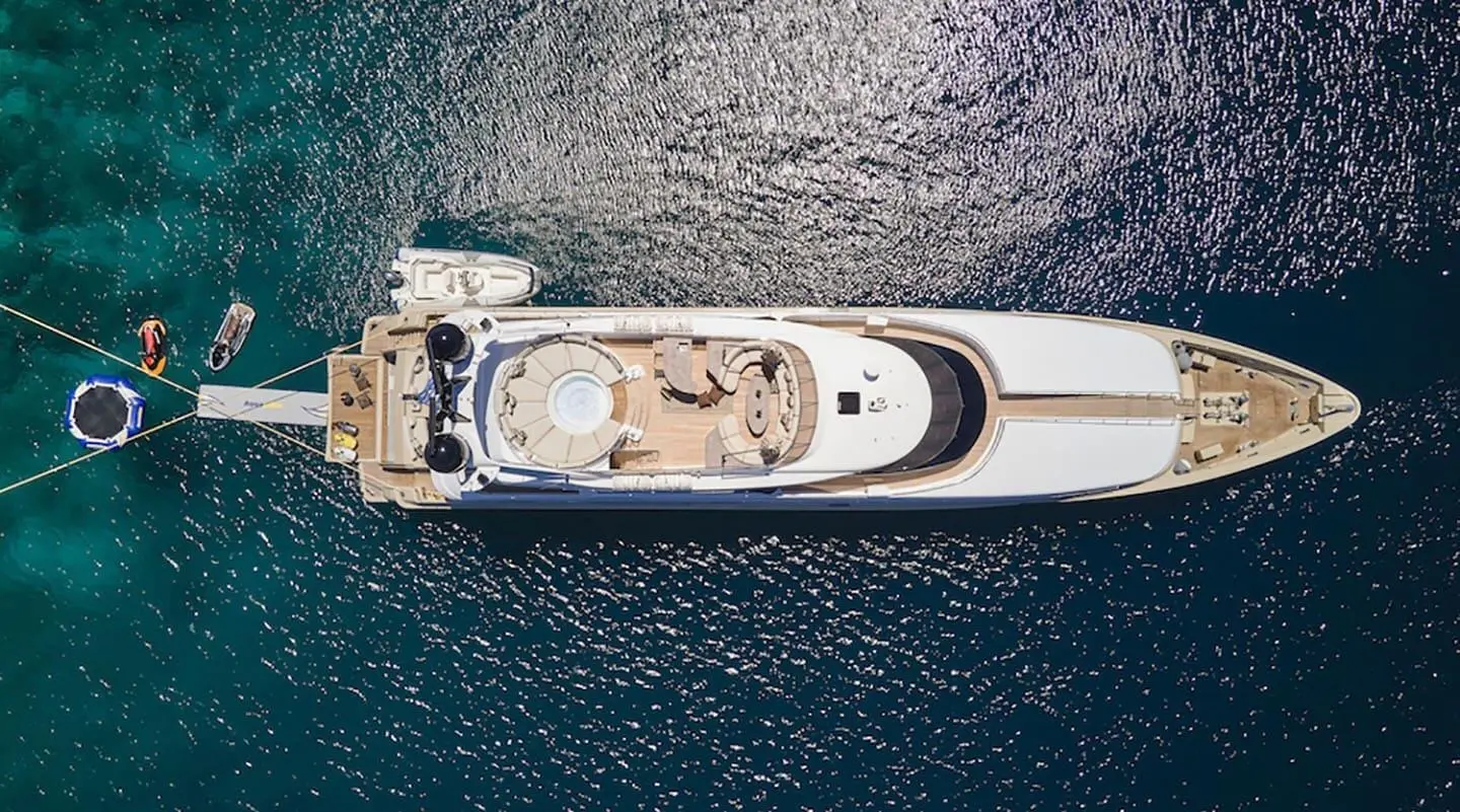 Aerial view of Daloli yacht with white deck and sunbathing area on blue water
