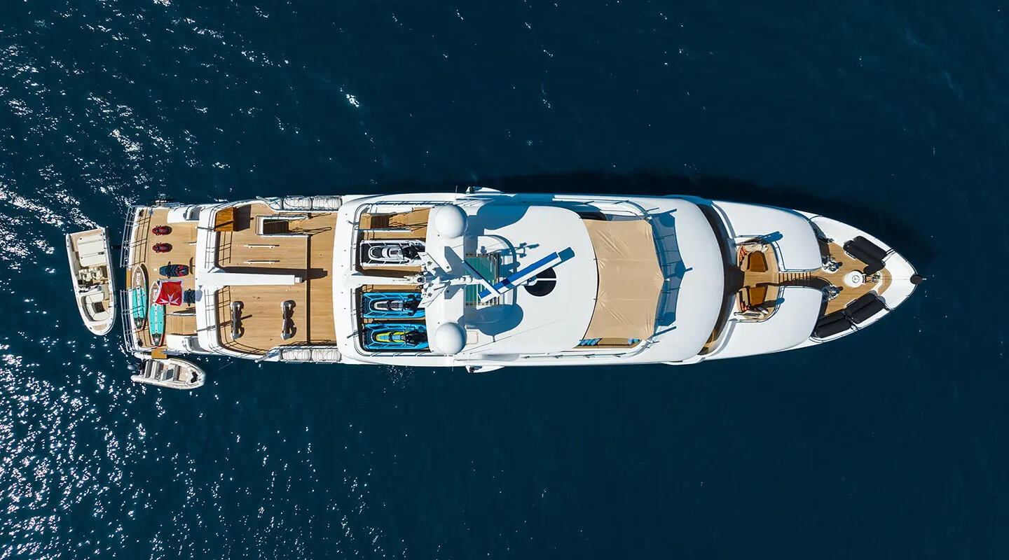 Top-down view of Serenity yacht anchored on calm blue water at dusk or dawn