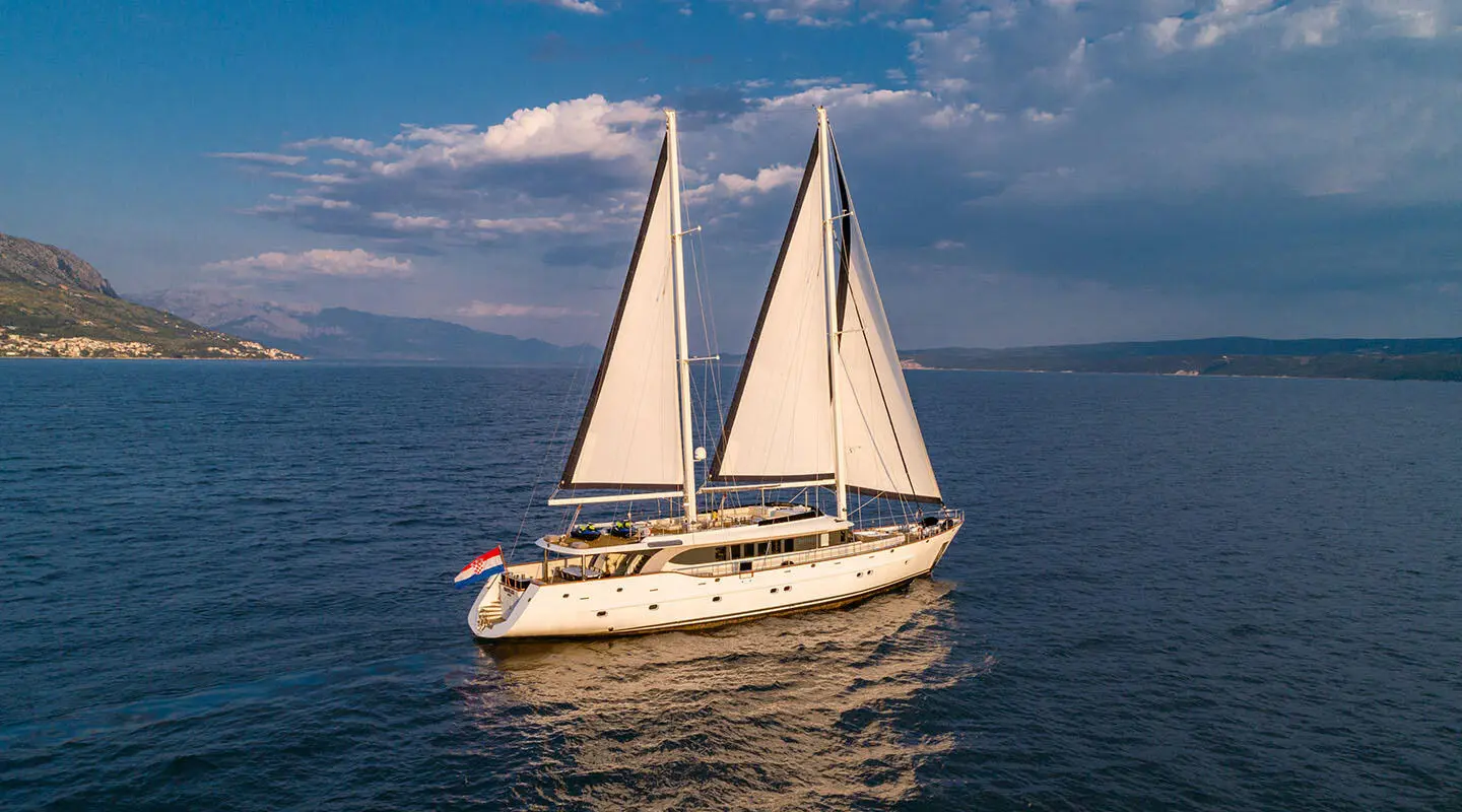 Navilux sailing yacht with three sails full on calm sea at sunset