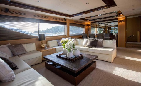 Interior of a luxury yacht with light-colored cushioned sofas and a coffee table