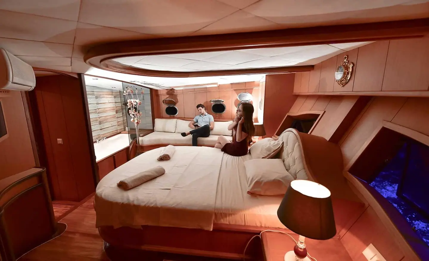 Blu Dream yacht cabin with large bed, seating area, warm lighting, and deck doorway
