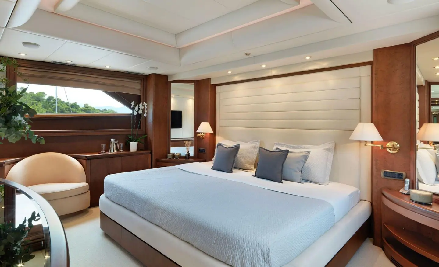 Idylle luxury yacht cabin with a neatly made bed, blue pillows, and warm wood accents