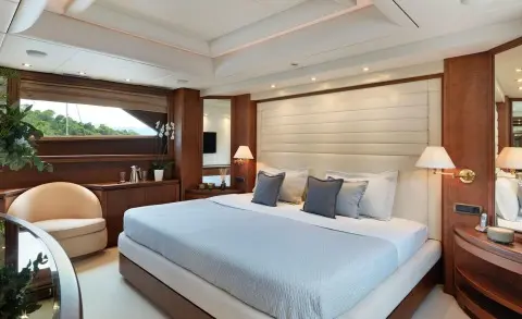 Idylle luxury yacht cabin with a neatly made bed, blue pillows, and warm wood accents