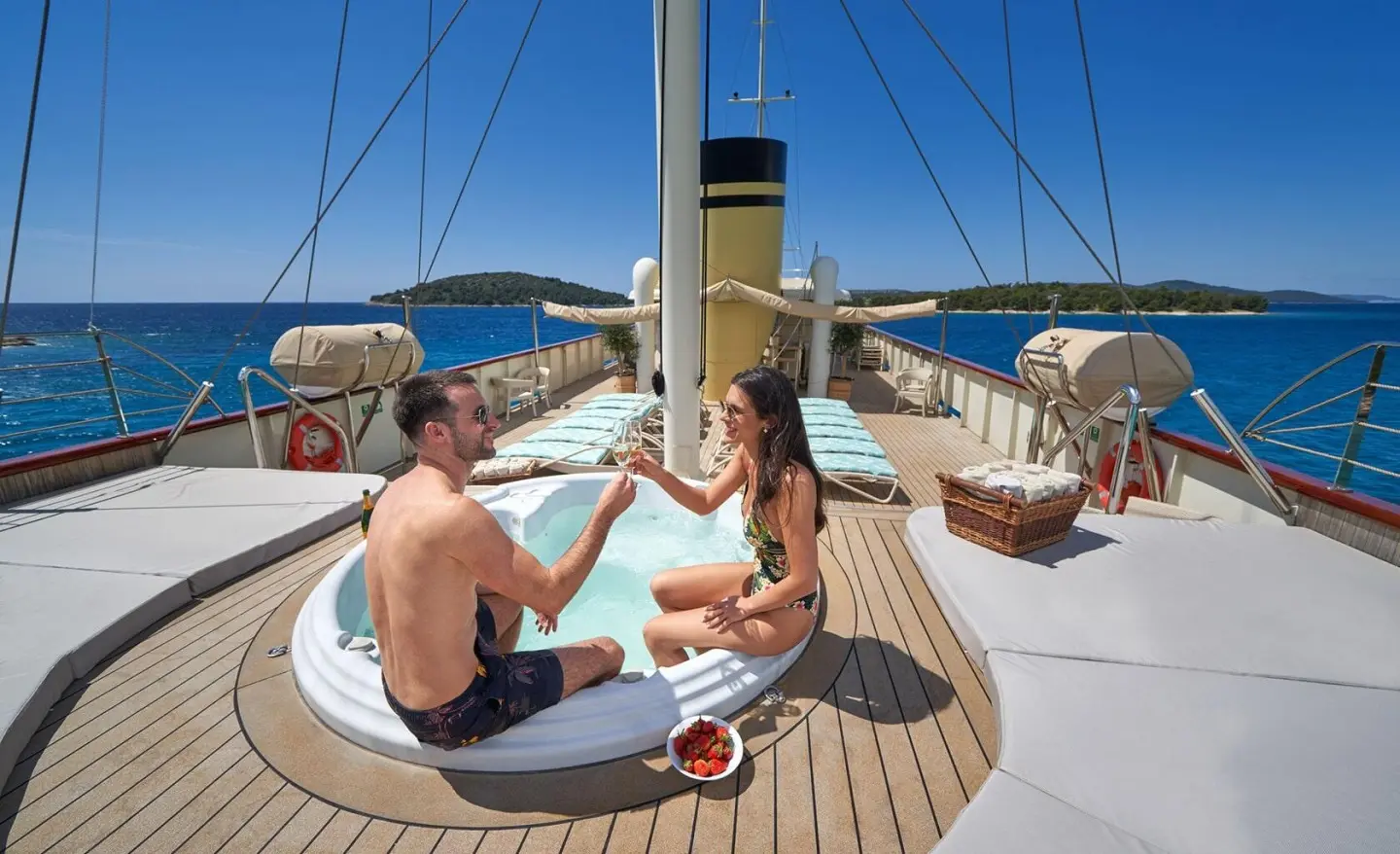 Couple clinking glasses in a hot tub on the yacht deck