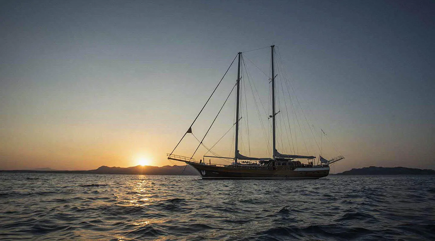 Sailing gulet with two masts at sunset on calm sea