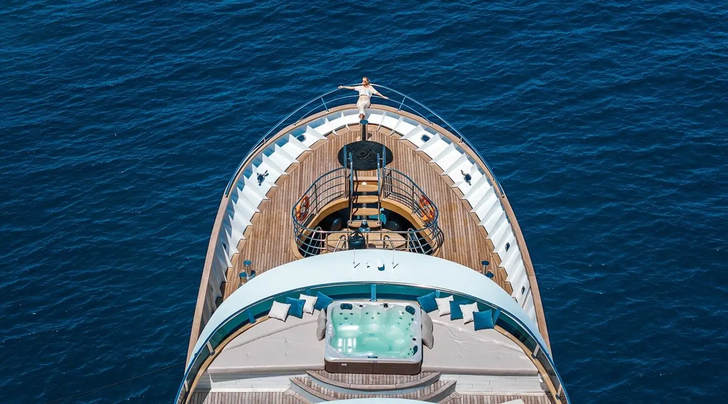 Top-down view of Bella yacht bow cutting through blue water, with deck details