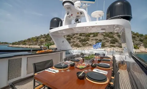 Pareaki II dining deck with table settings and sun loungers on yacht