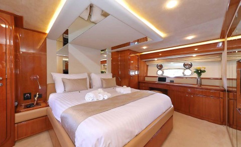 Quo Vadis I luxury yacht cabin with plush bed, glossy wood paneling, mirror accents, and soft ambient lighting