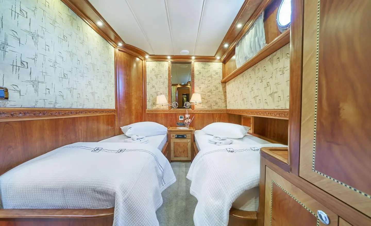 Luxurious Lotus yacht interior with two single beds, wood panels, and warm lighting