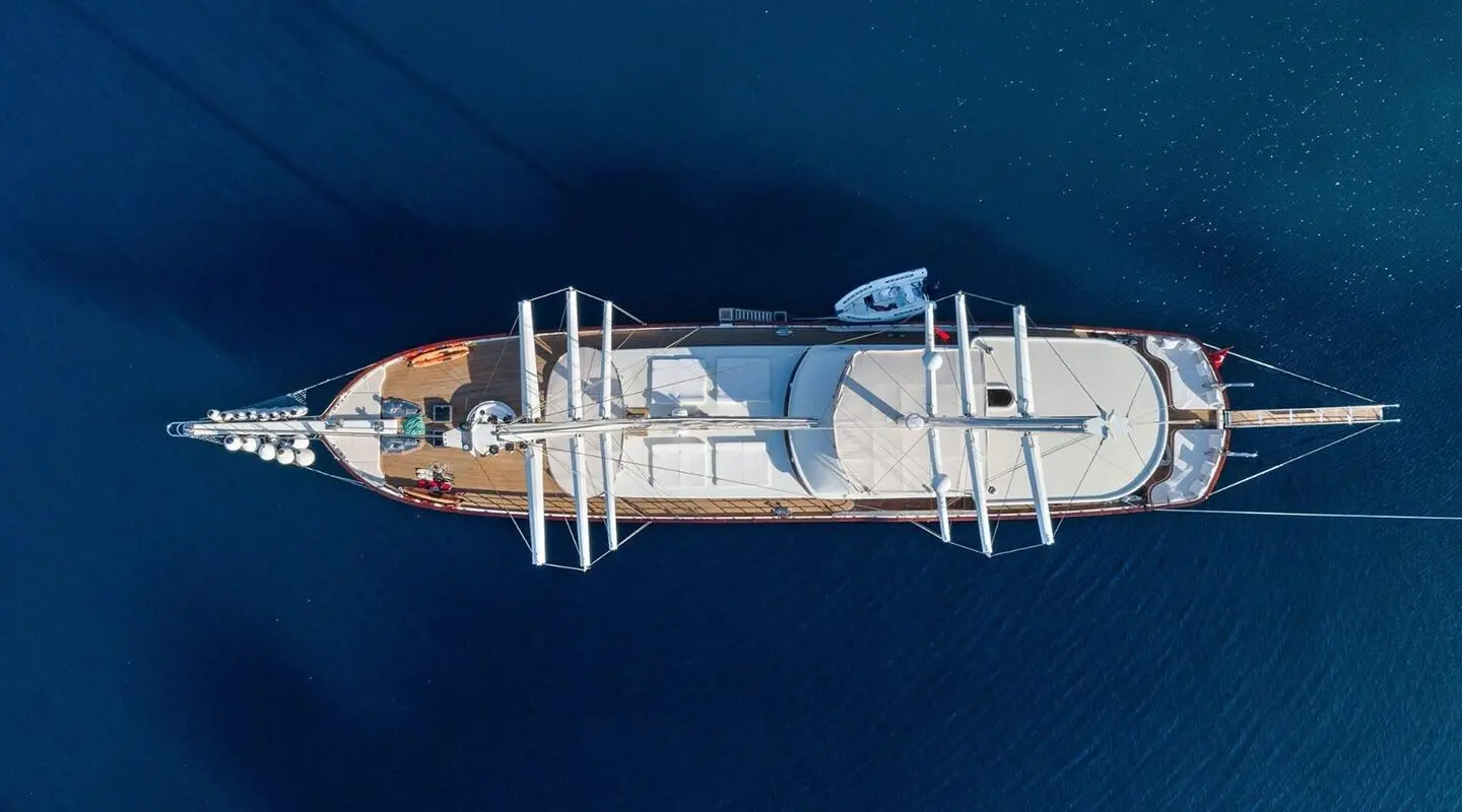 Top-down view of Halcon Del Mar yacht anchored in calm blue sea at sunset