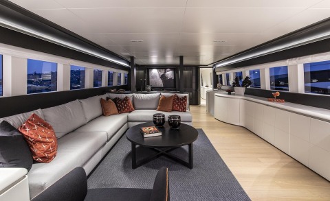 Interior lounge with gray sofa, black round coffee table, red cushions, wooden floor