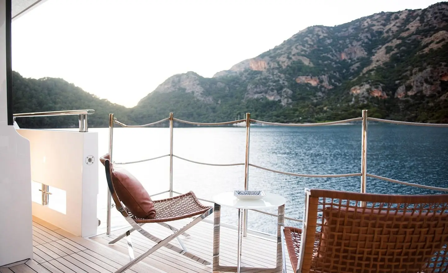 Morning Star yacht deck with chairs, calm water, hills in the background