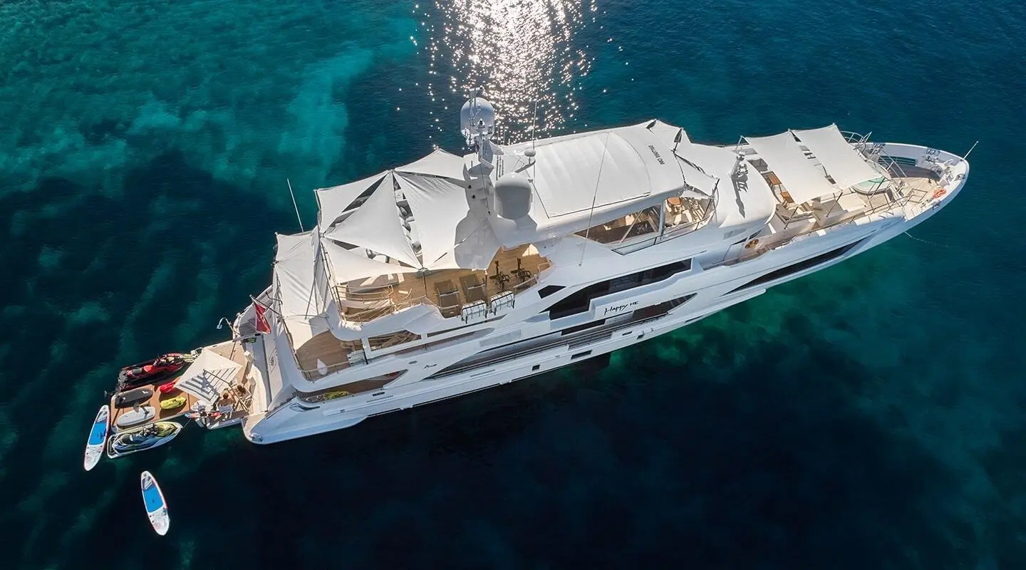 A white luxury motor yacht named Happy Me sails on clear blue water