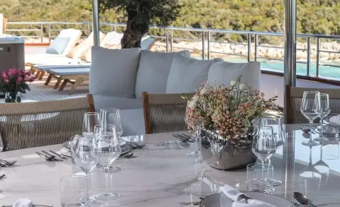 Table setting with a floral centerpiece and glassware on a dining table aboard a yacht