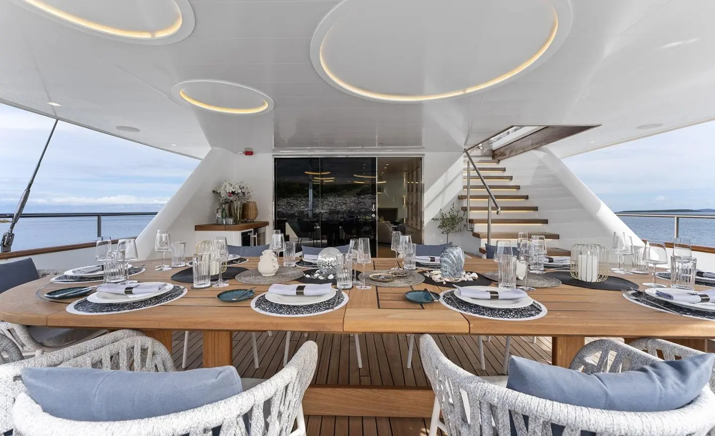 Maxita yacht dining deck with wooden table set for guests and white chairs