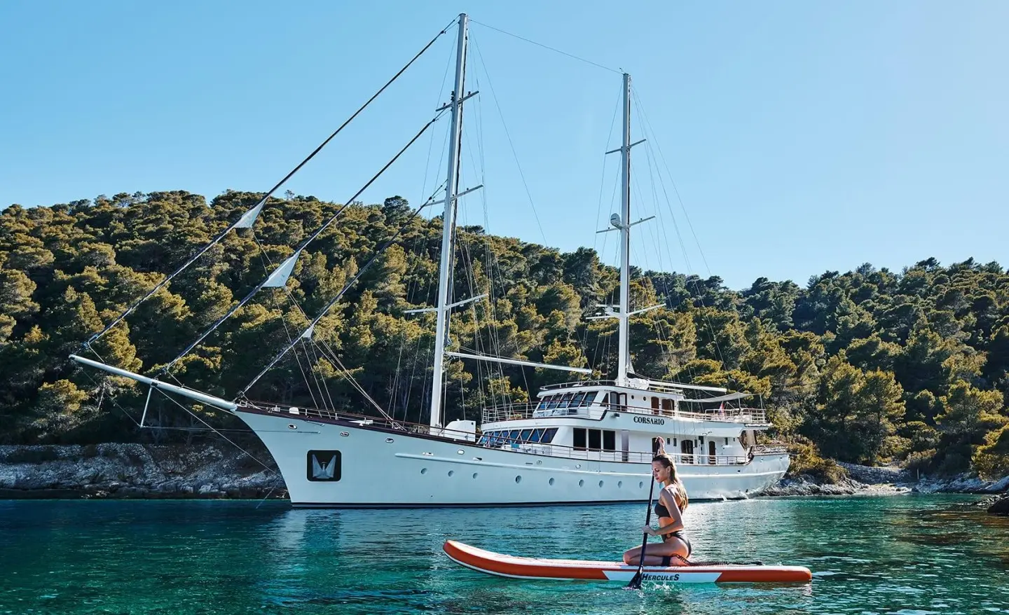 Corsario luxury gulet anchored near rocky coastline at sunset, calm sea