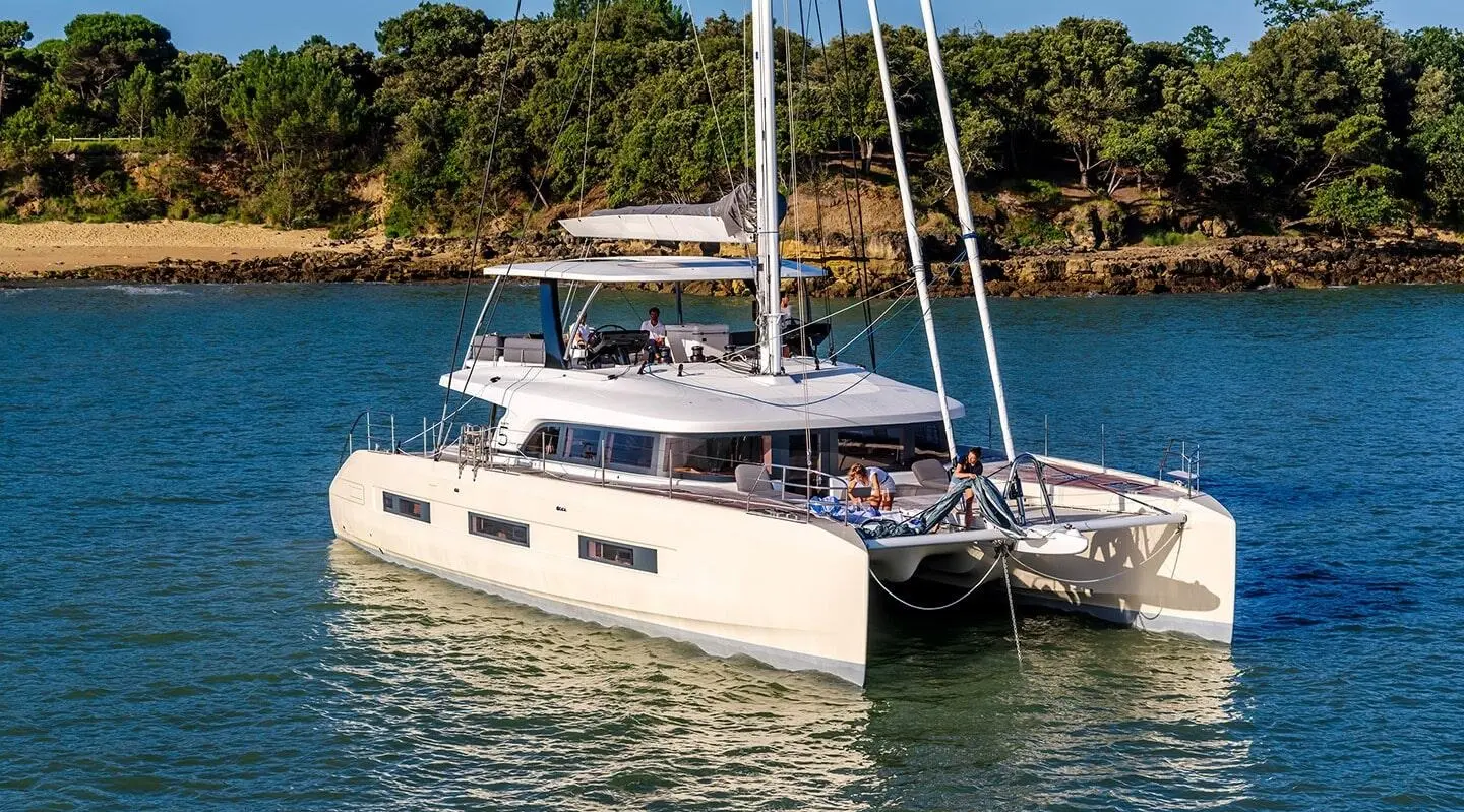 Daiquiri luxury yacht anchored near rocky coastline with palm trees, side view