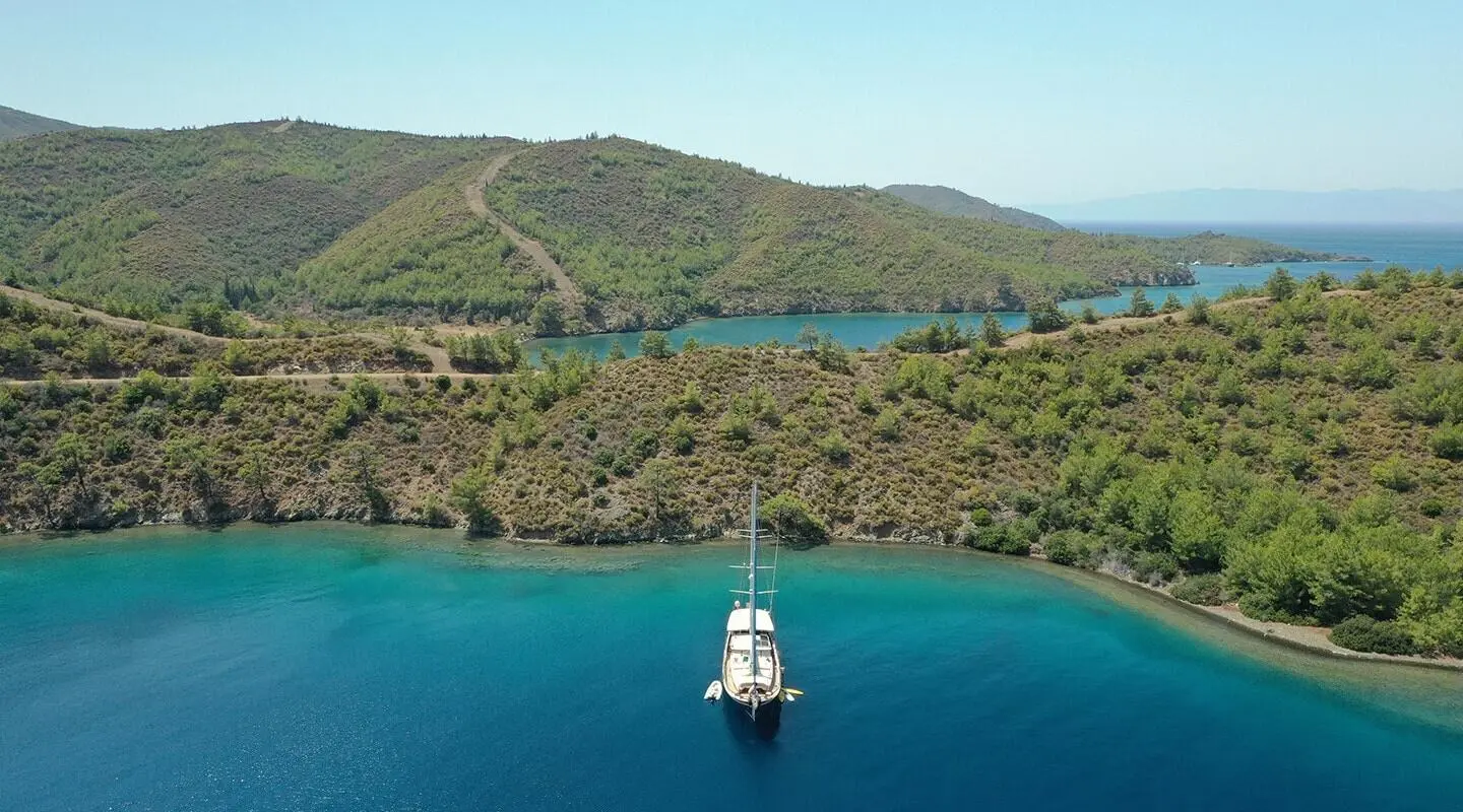 Enderim A yacht anchored in turquoise bay with green hills and clear blue water