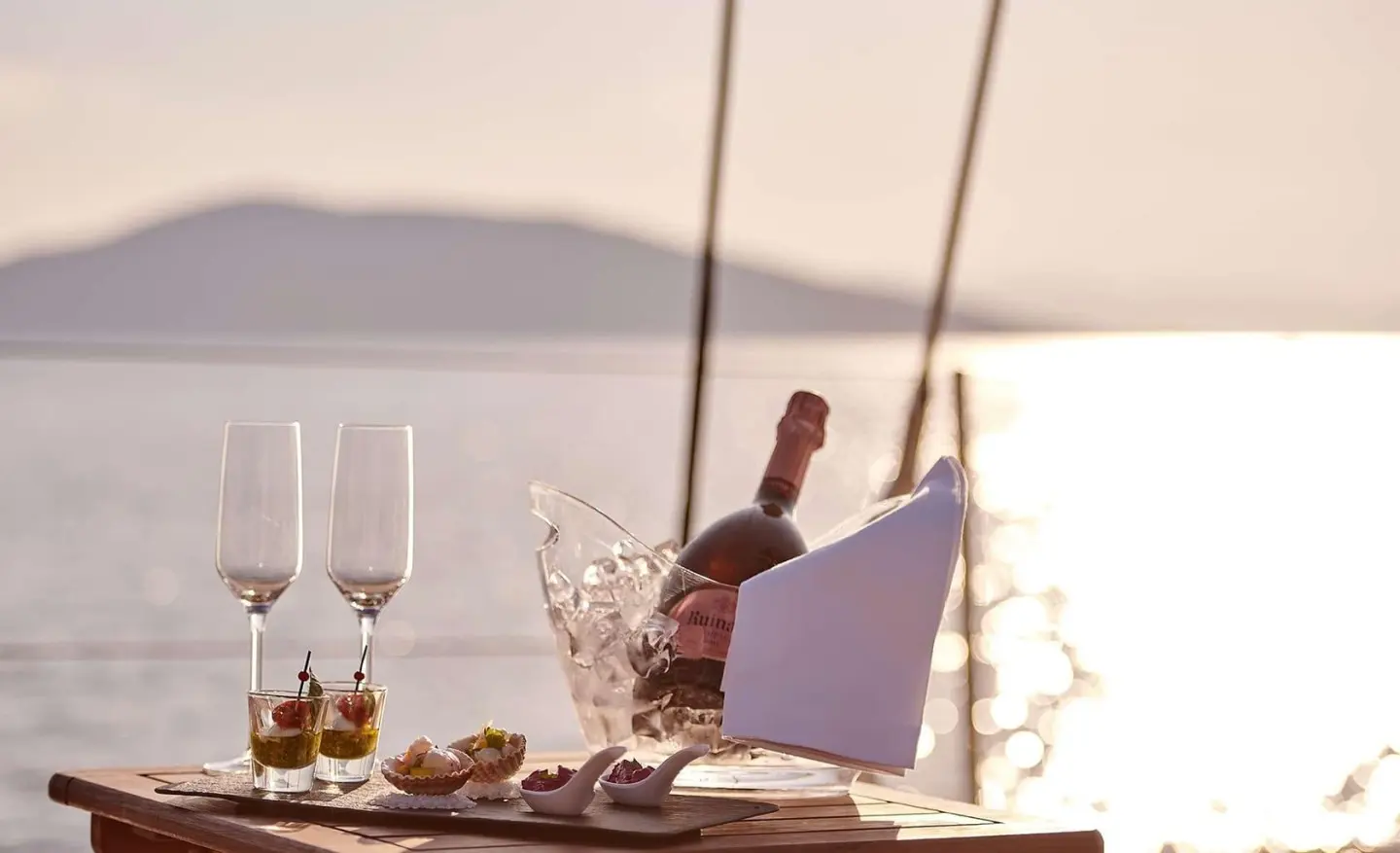 Aizu yacht sailing scene with sunset, champagne glasses on table, sailboat mast visible