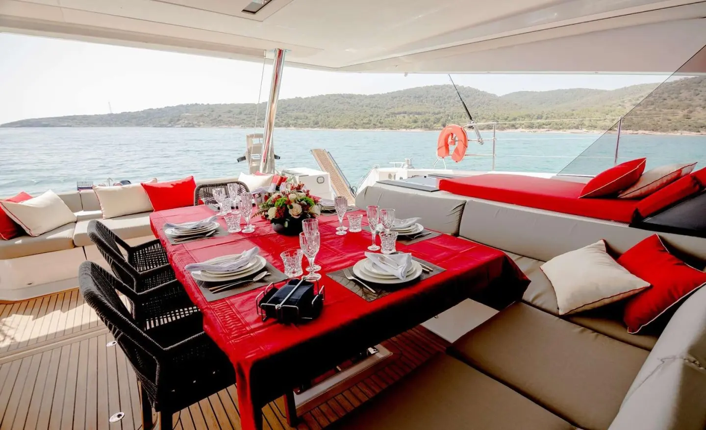 Astoria yacht dining setup on deck with red cushioned seating and sunset view