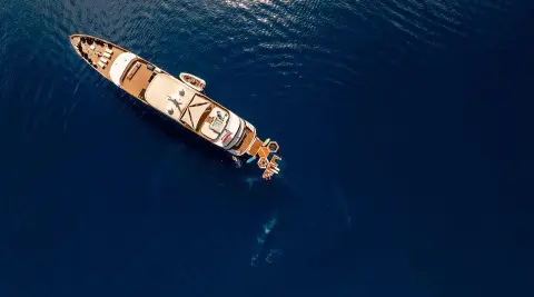 Yacht Cristal anchored in calm blue sea, viewed from above