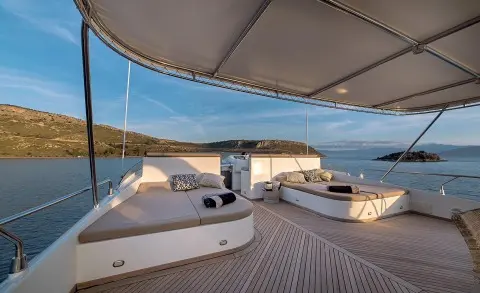 Aquila yacht deck with sun loungers and shaded seating on a harbor