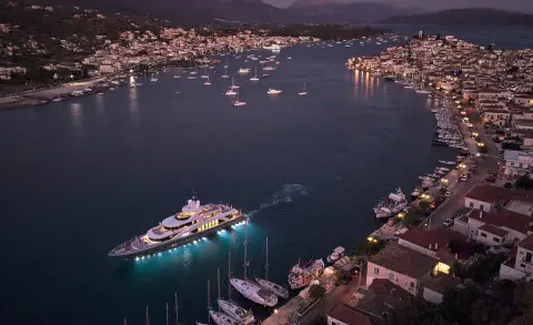 Luxurious yacht La Pellegrina 1 sailing in a harbor at night with lit coastal town