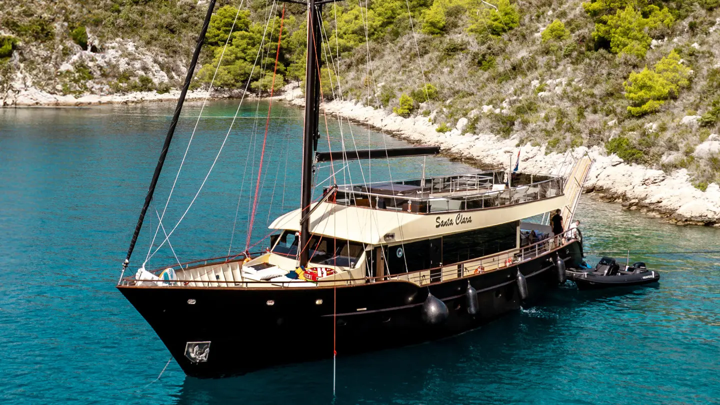 Santa Clara motor yacht anchored in turquoise water near rocky coastline