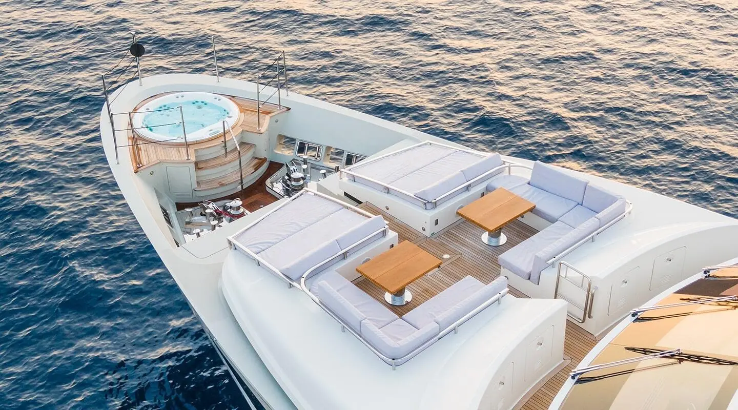 Aerial view of a luxury yacht with outdoor seating and hot tub on the deck